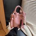Pink leather bucket bag featuring a knotted handle and colorful tassel charm accessory - Pink (With Pendant)