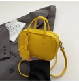 Dettaglio del ciondolo giallo con sorriso su una borsa a tracolla in pelle martellata - Giallo