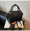 Détail du mini sac cabas noir en cuir grainé avec ferrures argentées sur des livres - Noir