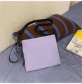 Detailed view of lilac nylon envelope bag with black strap on casual bedding scene - Purple