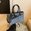 Bolso tipo cubo de mezclilla azul con asa de cuero negro y detalles metálicos dorados - Azul oscuro