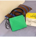 Minimalist green nylon crossbody bag for travel shown on blue surface background - Fruit Green