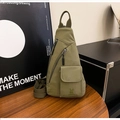 Detail der olivgrünen Canvas-Brusttasche mit Hasen-Logo auf einem Holztisch-Set - Grün