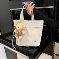 Chic beige canvas tote bag with cute bear charm and metallic logo on a kitchen background - White (With Charm)