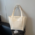 Minimalist cream white tote bag with front pocket shown on a stylish sofa background - Off-white