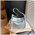 Gros plan du sac en cuir grainé bleu clair avec son fermoir rotatif doré iconique - Bleu Clair Avec Pendentif
