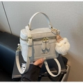Detail einer hellgrauen matten Leder-Eimertasche mit Goldbeschlägen und Plüschanhänger - Grau Mit Anhänger