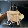 Detail der beigen Box-Tasche mit Goldreißverschlüssen, Logo und Plüschanhänger - Cremeweiß Mit Anhänger
