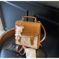 Detailansicht des braunen Lederrucksacks mit einem süßen weißen Bären-Plüschanhänger - Beige Mit Anhänger