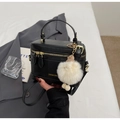Close-up of black crossbody bag with golden zipper and fluffy white pom-pom charm - Black with Pendant