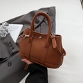 Kompakte braune Lederbeuteltasche mit Litschi-Muster, Griffen und verstellbarem Gurt - Braun