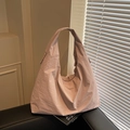 Bolso tote de nailon rosa empolvado con asa ancha sobre un sofá de cuero negro - Rosa