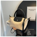 Detail van minimalistische crèmekleurige crossbodytas met zwarte flap en pluche hanger - Eén maat / Broken Wit