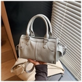Primer plano de bolso Boston gris con textura de lichi y remaches plateados - Gris
