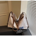 Detail of canvas tote bag showing TCT blue embroidery and brown leather trim on a sofa - Gray