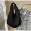 Detail of minimalist large black tote bag showing durable fabric and crescent silhouette - Black