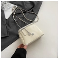 Détail d'un sac bandoulière en cuir crème avec bandoulière chaîne et breloque camélia - Petit / Blanc