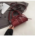 Detail of burgundy cross-lace design and silver eyelets on a retro shoulder bag - Red