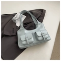 Dettaglio della borsa tote azzurra con tasche anteriori e fibbie metalliche lucide - Blu