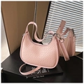 Pink crescent shoulder bag with embossed texture and silver hardware in a lifestyle setting - Pink