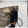 Detail of a black leather bucket bag with drawstring closure and metal buckle hardware - Black