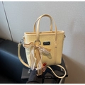 Détail du sac seau jaune pâle avec texture tissée, logo en métal et nœud en dentelle - Avec Pendentif / Jaune