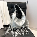 Zilveren metallic hobo schoudertas met franjes en strik op een zwarte leren stoel - Zilver