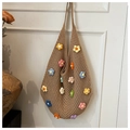 Dettaglio di fiori all'uncinetto 3D colorati e trama a rete su borsa intrecciata beige - Cachi