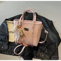 Gros plan sur un sac cabas rose tressé avec plaque argentée et nœud en dentelle - Avec Pendentif / Rose
