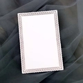 White laser cut lace paper card with hollow floral border on dark grey tulle background - White