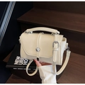 Detalle de bolso bandolera crema con hebilla plateada y textura de cuero sintético de calidad - Blanco Roto