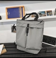 Vista dettagliata della borsa tote in tela grigia con doppie tasche e tracolla in nylon su tavolo - Grigio