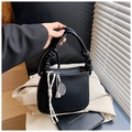 Detail of lychee pattern leather bucket bag with woven knot handle and tennis pendant - Black