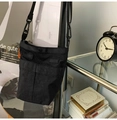 Detail of minimalist nylon crossbody bag with contrast orange tag and adjustable strap - Black