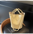 Detail of creamy yellow bucket bag with lychee grain leather texture and metallic studs - Yellow