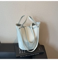 Detailansicht der hellblauen Eimer-Tasche mit Litschi-Struktur auf Designer-Büchern - Blau