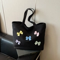 Black canvas tote bag featuring five colorful polka dot bows and textured waffle fabric - Black