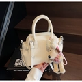 Primer plano del bolso crema con textura lichi y colgante de perro de peluche - Con Colgante / Blanco Roto