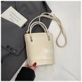 Sac seau chic en cuir crème avec détails argentés sur fond de blazer gris - Sans pendentif / Blanc