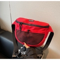 Detail of red nylon chest bag featuring mesh pocket and adjustable black strap on a sofa - Red