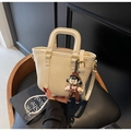 Kleine cremefarbene Eimer-Tasche aus Kunstleder mit süßem Puppenanhänger und Golddetails - Hellkhaki Mit Anhänger