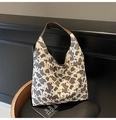 Detalle del bolso tote de lona con estampado de vaca y asas de cuero marrón en silla - Bolso de Mano con Asa de Cuero Marrón / Estampado de Vaca Grande