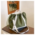 Close-up of olive green nylon tote bag with drawstring detail and white canvas straps - Green