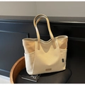 Detail van een grote canvas draagtas met beige stiksels en hoogwaardige lederen accenten - Beigegrijs