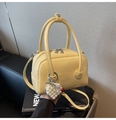 Detail of yellow lychee pattern leather bag featuring a heart pearl pendant and dual zippers - With Charm / Yellow