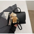 Detail einer schwarzen strukturierten Handtasche mit Metallverschluss und Bärenanhänger - Schwarz Mit Anhänger