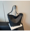 Gros plan sur la texture du cuir noir grainé et le logo discret embossé du sac seau chic - Noir
