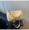 Close-up of beige woven texture crossbody bag featuring a silver floral chain strap - Yellow