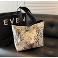 Detail of silver tote bag with black bamboo ink pattern on a black leather sofa - Off White
