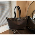 Close-up of black tote bag featuring premium leather patchwork and metallic zip closure - Black